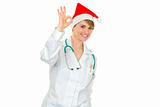 Smiling female medical doctor in Santa hat showing ok gesture
