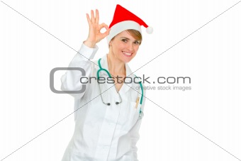 Smiling female medical doctor in Santa hat showing ok gesture

