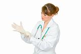 Concentrated female doctor wearing latex medical gloves on her hand
