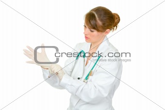 Concentrated female doctor wearing latex medical gloves on her hand 