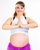 Smiling beautiful pregnant woman doing yoga exercises at home
