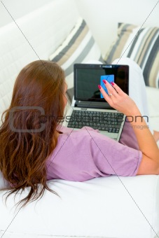 Woman sitting on sofa and using credit card to shop from  internet
