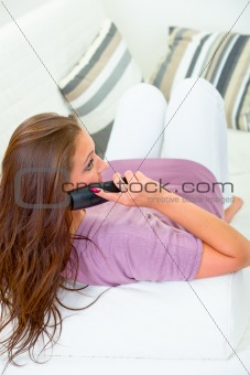 Serious pretty woman sitting on sofa  and  talking on phone 
