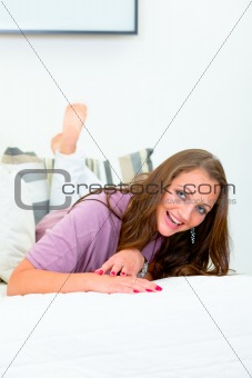 Laughing attractive woman lying on white sofa
