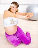 Smiling beautiful pregnant female doing fitness exercises at  home
