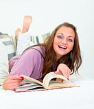 Laughing pretty woman lying on couch with book
