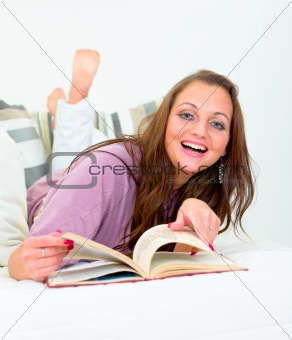Laughing pretty woman lying on couch with book
