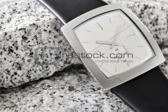 The arm watch with the leather strap on stone