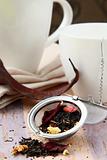tea strainer with a fragrant black tea and cups in the background