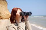 Girl with binocular at the beach.