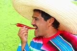 Mexican man poncho sombrero eating red hot chili