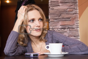 Young blonde in a cafe waiting for a call