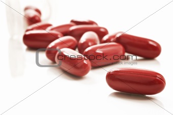 Red pills and pill bottle  on white background