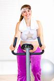Smiling beautiful pregnant woman working out on static bike
