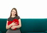 Woman cuddling with a heart pillow