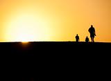 Three people silhouetted in sunset