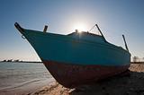 Derelict boat on a beach with sun