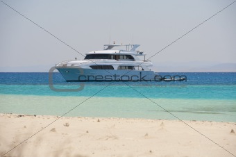 Large motor yacht moored off a tropical beach