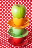 Green apple and bright cup with a red background
