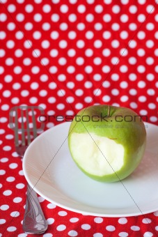Green apple on a white plate on a red background