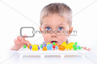 Little cute boy playing with multicolored mosaic
