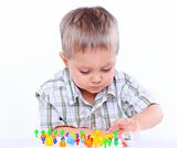 Little cute boy playing with multicolored mosaic