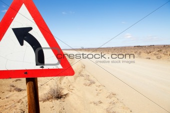 Triangular road sign indicating left turn