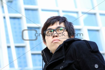 Image of pensive guy looking aside on the background of modern office building 