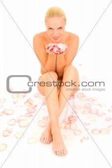 nude woman sitting between rose petals