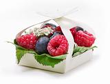 Ripe raspberry and blueberries with green leaf on white background