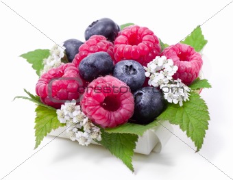 Ripe raspberry and blueberries with green leaf on white background