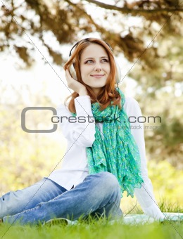 Redhead girl with headphone in the park. 