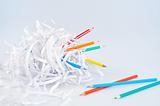 Colored pencils and shredded paper ball over light blue background with soft shadow - concept