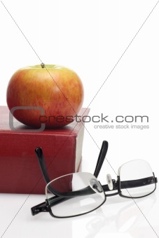 Apple, reading glasses and book