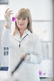 female researcher holding up a test tube in lab