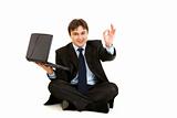 Sitting on  floor with laptop smiling businessman showing ok gesture
