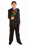 Full length portrait of smiling modern businessman with red rose in hand
