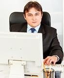 Modern businessman sitting at office desk and working on pc
