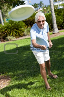 Happy Senior Man Throwing Frisbee Outside in Sunshine