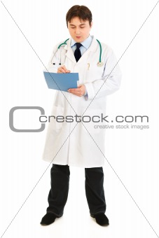 Full length portrait of serious doctor making notes in medical chart
