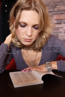Portrait of a young pretty girl in cafe with a book