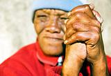 Old African woman with folded hands - focus on the weathered hands