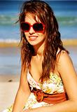 Pretty girl with red sunglasses on the beach