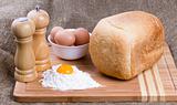 Yolk, eggs of house hens, salt, pepper and fresh hot home-made bread with wheat flour on kitchen to a board