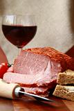 large piece of ham in pepper with a glass of red wine