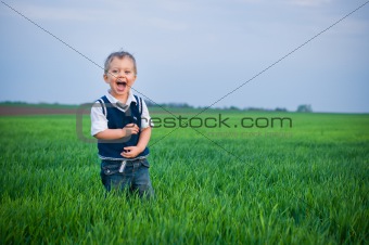 A beautiful little boy staing in the grass