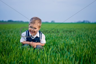 A beautiful little boy sitting in the grass