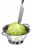 Cabbage in a colander with a knife on white isolated.
