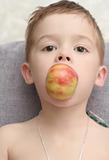 The boy which holds an apple a mouth