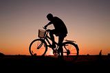Man and bike silhouette in orange sunrise